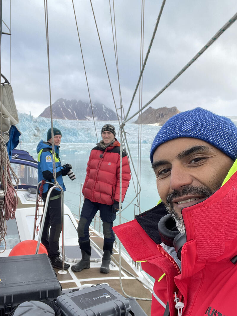 Expedition på båt i Arktis bland isberg gör en selfie men breda leenden. 