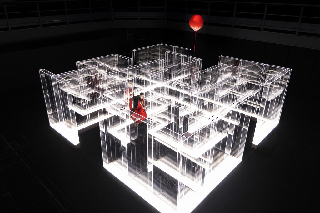 Kvinna instäng i en labyrint på scen som är häftigt upplyst med mörk bakgrund