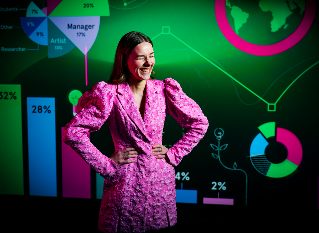 Kvinna ler på bild i bakgrunden syns ett par färgglada grafer